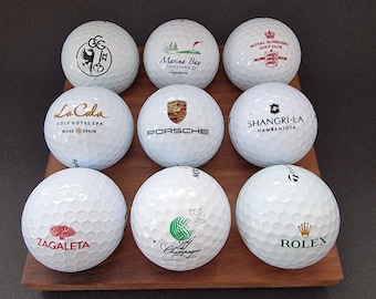 Soporte piramidal para pelotas de golf, fabricado en madera maciza de nogal, con capacidad para hasta 14 pelotas.