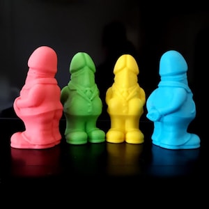 Può includere: Quattro piccole statuette in piedi in colori vivaci e solidi: rosa, verde, giallo e blu. Ogni statuetta presenta una testa arrotondata di forma fallica sopra un busto che indossa una giacca con colletto e bottoni e pantaloni. Le figure sono allineate.