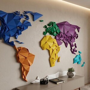 Puede incluir: Una colorida instalación de arte mural con un mapa del mundo geométrico. Los continentes están representados en tonos de azul, naranja, amarillo, verde, morado y turquesa. La obra de arte está montada en una pared de tono neutro, con un mueble gris y decoración debajo.