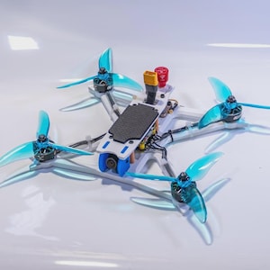 May include: A white and black drone with four light blue propellers. The drone has a black top and a blue camera. It has a red and yellow component on top.