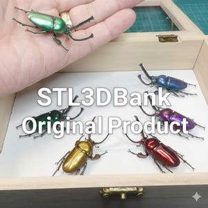 Puede incluir: Figuras de escarabajos con acabado metálico en varios colores: verde, azul, morado, dorado y rojo. Se exhiben en una caja de madera con el texto "STL3DBank Original Product".