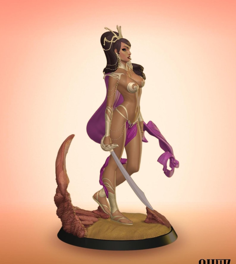 Puede incluir: Figura de fantas&iacute;a de una mujer con capa morada y armadura dorada, sosteniendo una espada. La figura se alza sobre una base con textura arenosa y borde oscuro. La mujer tiene cabello oscuro y est&aacute; adornada con joyas.