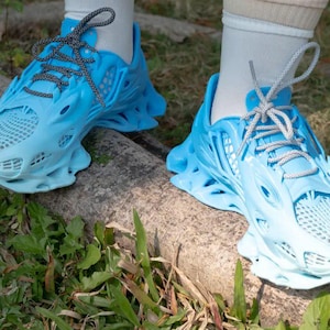 May include: A pair of blue and white athletic shoes with a unique, intricate design. The shoes have a mesh-like upper and a thick, textured sole.