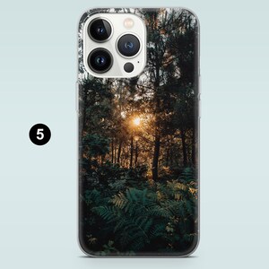 May include: A phone case with a photo of a forest scene. The photo shows a sun shining through the trees and green ferns in the foreground.