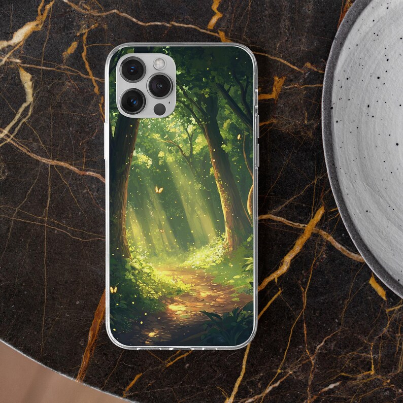 May include: A clear phone case with a colorful image of a forest path with sunlight streaming through the trees. The image features a green and brown forest with a path leading into the distance.