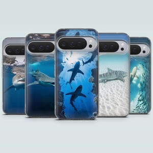 May include: Five smartphone cases arranged in a row, each featuring a distinct underwater scene with sharks. The designs include a great white shark, a whale shark, silhouettes of sharks in deep blue water, a tiger shark, and a shark near fish.