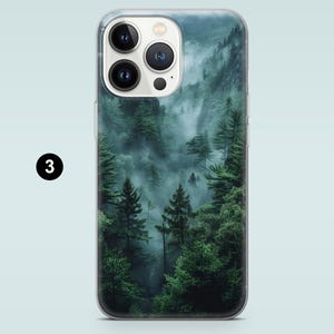 May include: A phone case with a misty forest scene. The image features a lush green forest with fog rolling through the trees. The phone case is clear and shows the phone's camera lens.