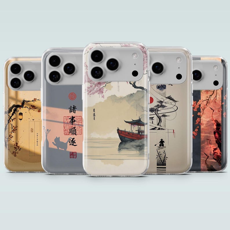 May include: Five clear phone cases with Japanese-inspired art. Each case features a different design, including a boat on water, cherry blossoms, and a red sun. The cases have a transparent border and a black camera module.