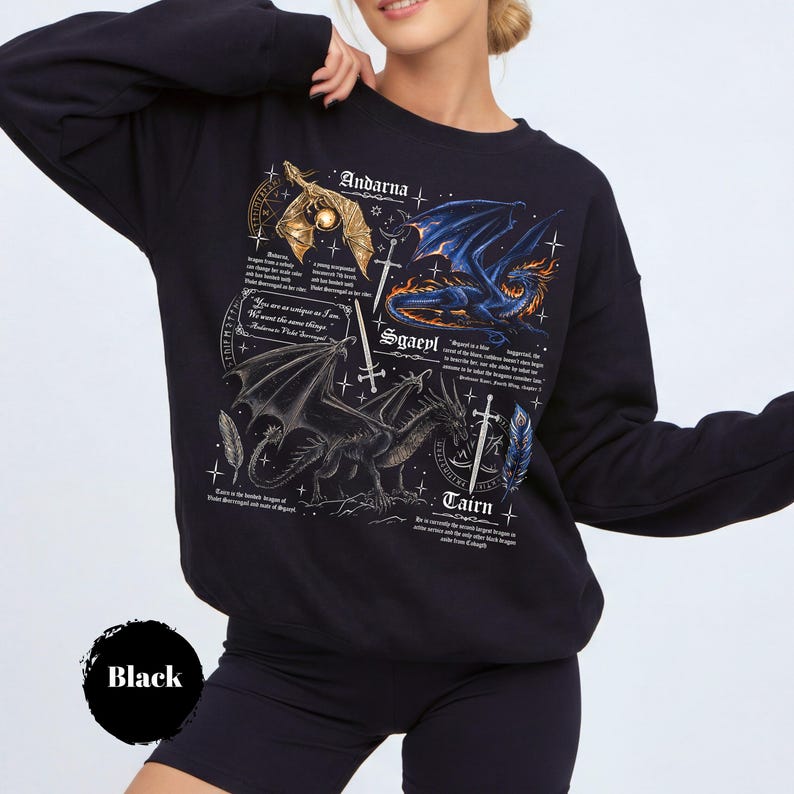 May include: A black long-sleeve sweatshirt featuring a detailed graphic print of three dragons named Andarna, Sgaeyl, and Tairn. The design includes intricate illustrations of the dragons, swords, feathers, and descriptive text blocks in white font.