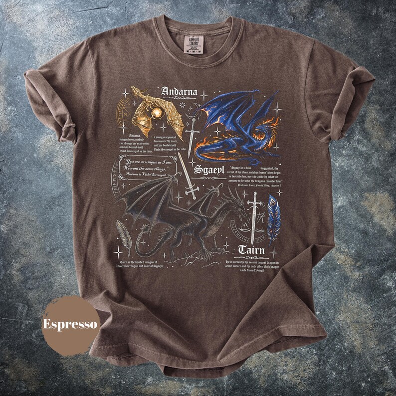 May include: An espresso-colored short-sleeve t-shirt featuring a graphic print of three dragons labeled Andarna, Sgaeyl, and Tairn. The design includes detailed illustrations of dragons, swords, feathers, and small text excerpts from the Fourth Wing book series.