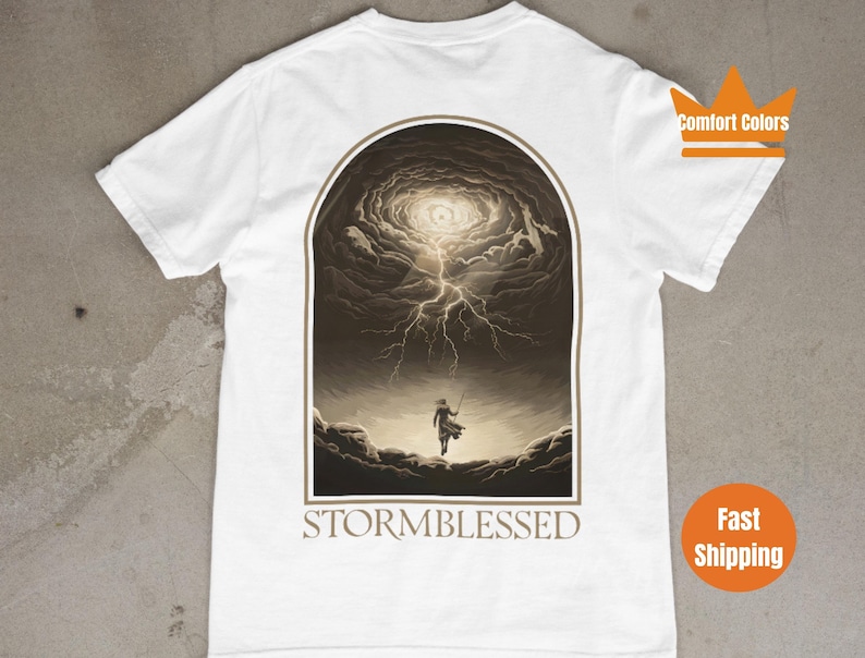 Puede incluir: Camiseta blanca con un estampado gr&aacute;fico de una persona caminando hacia una nube de tormenta con rayos. El texto "STORMBLESSED" est&aacute; impreso debajo del gr&aacute;fico.