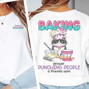 May include: White sweatshirt with the text "Queen of Baking" on the front and a graphic of a cat wearing a chef's hat on the back. The back graphic includes the word "BAKING" and the phrase "because punching people is frowned upon."