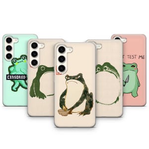 Puede incluir: Una colección de fundas para teléfonos con diseños de ranas. Las fundas muestran varias ilustraciones de ranas, incluyendo estilos pixelados, de pinceladas y de dibujos animados. Algunas fundas tienen texto que dice "CENSORED" y "TEST ME". Las fundas son en tonos verdes, beige y rosa.