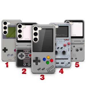 以下が含まれることがあります： レトロな携帯ゲーム機のデザインが施された、グレーと透明のスマートフォンケース5点。各ケースにはカメラ用の切り抜き、画面グラフィック、十字キー、アクションボタンがあります。ケースには赤字で1から5までの番号が振られています。