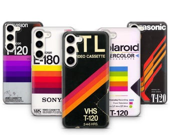 May include: A collection of phone cases with retro VHS tape designs. Each case features a different brand and design, including vibrant color schemes and text such as "VHS T-120" and "Video Cassette". The cases are designed to fit a smartphone.