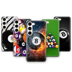 May include: Five different phone cases with a billiard theme. The cases feature a variety of designs, including a black and white striped case with a billiard ball, a case with a close-up of a billiard ball, a case with a green background and billiard balls, a case with a black background and a billiard ball, and a case with a colorful design of billiard balls and flames.