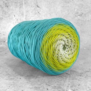 Può includere: Un rotolo di filato ombré turchese e giallo. Il filato è avvolto in una bobina stretta.