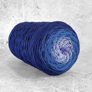 Peut inclure: Une pelote de fil ombré bleu avec un dégradé du bleu foncé au violet clair. Le fil est enroulé en forme de boule et est prêt pour le tricot ou le crochet.