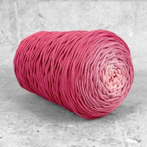 Op de afbeelding: Een bol felroze garen met een kleureffect, van diep fuchsia naar een lichter roze in het midden. Het garen is strak opgerold, wat een textuur creëert. Perfect voor breien of haken.