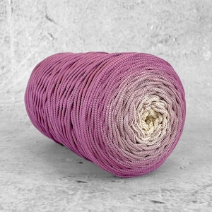 Peut inclure: Un rouleau de cordon en coton ombré rose et crème, parfait pour le macramé ou d'autres travaux manuels.