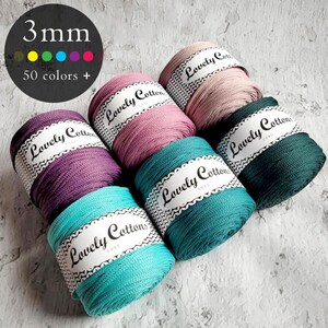 Puede incluir: Seis bobinas de cordón de 3mm en varios colores incluyendo turquesa, morado, rosa y verde oscuro. Cada bobina tiene una etiqueta de papel blanco con el texto Lovely Cotton. Un gráfico circular negro en la esquina muestra 3mm y 50 colors +.