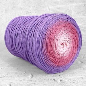 Peut inclure: Une bobine cylindrique de cordon présentant un dégradé de couleurs passant d'un violet profond sur les bords extérieurs à un magenta vif, puis à un rose tendre, et enfin à un blanc pâle au centre de la bobine étroitement enroulée.
