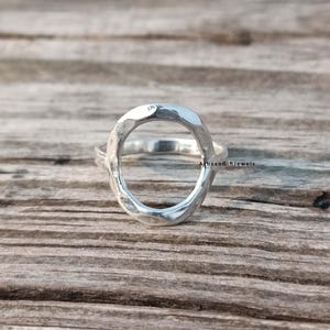 Peut inclure: Une bague en argent avec un design martelé de forme ovale. La bague est ouverte et a une finition lisse et polie.