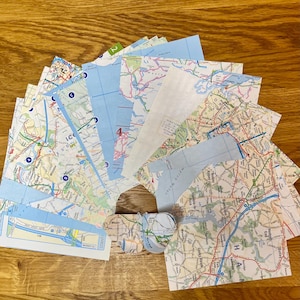 Peut inclure: Un ensemble de cartes routières anciennes, disposées sur une surface en bois. Les cartes présentent des réseaux routiers détaillés, des villes et des éléments géographiques, avec des teintes bleues et vertes. Certaines cartes comportent des chiffres et du texte, dont "ICO" et "STANST".