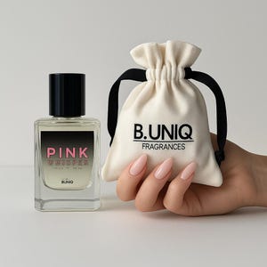 May include: A clear glass perfume bottle with a black cap and the words "PINK WHISPER" in pink. A small cream-colored drawstring bag with the text "B.UNIQ FRAGRANCES" is held in a hand.