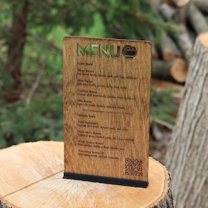 May include: A wooden menu board with the word "MENU" in gold lettering at the top. The menu lists various ramen dishes, including Shoyu Ramen and Spicy Tantanmen. The board is displayed on a tree stump.