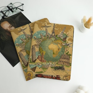 May include: Two travel-themed notebooks with a world map design. The covers feature illustrations of famous landmarks like the Eiffel Tower, Leaning Tower of Pisa, and the Colosseum. The notebooks are tan with a vintage aesthetic.