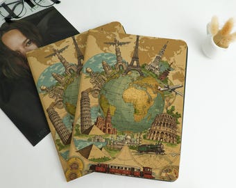 May include: Two travel-themed notebooks with a world map design. The covers feature illustrations of famous landmarks like the Eiffel Tower, Leaning Tower of Pisa, and the Colosseum. The notebooks are tan with a vintage aesthetic.