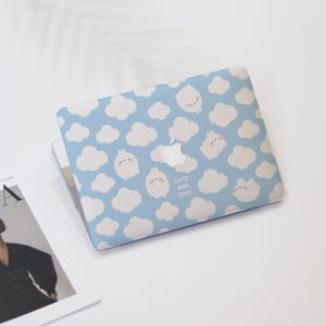 May include: A blue laptop skin with a white cloud and bunny pattern. The text "Cute and Cozy" is printed on the skin.