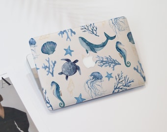 May include: A laptop hard shell case featuring a watercolor print of various marine life including a blue whale, sea turtle, seahorses, jellyfish, starfish, seashells, and coral branches on a light background with a central apple logo cutout.