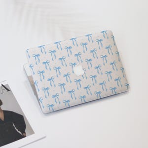 May include: A white laptop computer with a blue bow pattern on the lid. The Apple logo is visible on the lid.