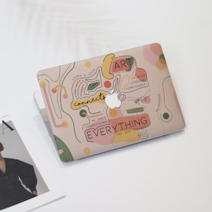 May include: A laptop with a decorative cover featuring the word "ART" and the phrase "EVERYTHING can you connect?" in a playful design with abstract shapes and lines in pink, green, and yellow.
