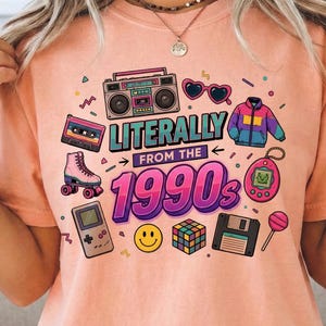 May include: Peach-colored t-shirt with a colorful graphic design featuring a boombox, roller skate, and the text "Literally from the 1990s." Other graphics include a smiley face, Rubik's cube, and a floppy disk.