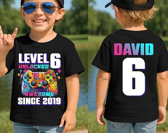 Könnte beinhalten: Schwarzes T-Shirt mit "LEVEL 6 UNLOCKED AWESOME SINCE 2019" und einer bunten Videospiel-Controller-Grafik. Auf der Rückseite des Shirts stehen der Name "DAVID" und die Zahl "6".