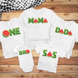 May include: White t-shirts and a onesie with watermelon-themed text. The shirts say "ONE", "MAMA", "DADA", and "SAS". The onesie says "BRO". The text is green with red watermelon slices.