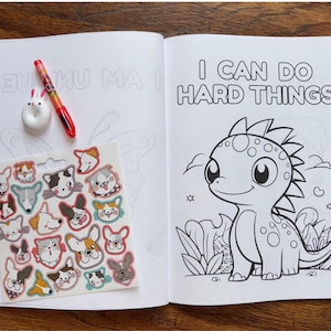 May include: A coloring book with a black and white illustration of a dinosaur with the text "I can do hard things". The book comes with a sheet of stickers featuring various animal faces.
