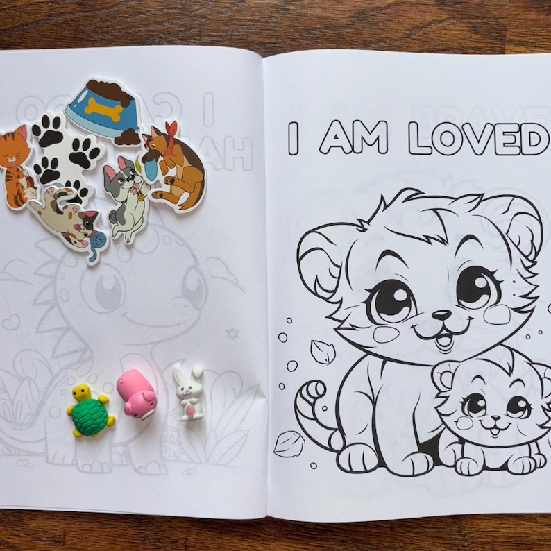 May include: A black and white coloring book with a page that says "I am loved" and features a cartoon tiger with a baby tiger. The page is surrounded by paw prints and other animal stickers.