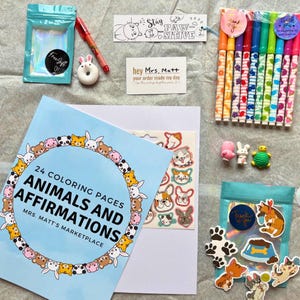 May include: A blue and white coloring book with 24 coloring pages of animals and affirmations. The book is titled "Animals and Affirmations" and has the text "Mrs. Matt's Marketplace" on the cover. The book is surrounded by a variety of colorful items, including stickers, markers, and a small toy.