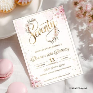 May include: A floral 70th birthday invitation with gold script reading "Seventy". The invitation includes event details and is decorated with pink floral accents and gold flecks. Macarons and pastries are visible in the background.
