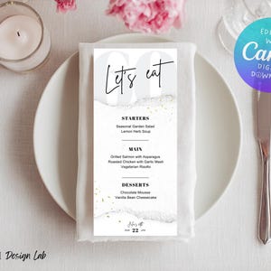 May include: A menu card with the text "Let's eat" in elegant script. The menu lists starters, main courses, and desserts, including seasonal garden salad, grilled salmon, and chocolate mousse. The card is on a white napkin, with a plate, silverware, and a candle.