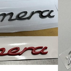 May include: Two car emblems, one black and one red, both with the word "Panamera" in a stylised font.