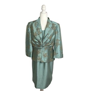 May include: A two-piece formal suit in a seafoam green color, featuring a jacket and a knee-length skirt. The jacket has a floral pattern in a contrasting gold color, with three-quarter sleeves and a gathered front. The skirt is a solid seafoam green.