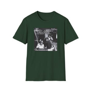 May include: Dark green t-shirt featuring a black and white image of jazz musicians. The image includes the text "MONEY JUNGLE, DUKE ELLINGTON, CHARLIE MINGUS, MAX ROACH". The shirt is a classic crew neck style.