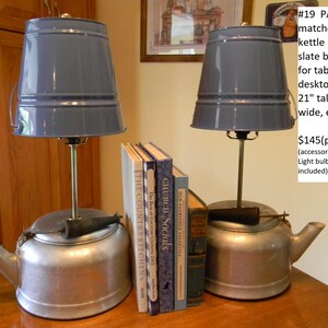 May include: A pair of repurposed kettle lamps with slate blue shades. The lamps are 21 inches tall and 11.5 inches wide. The lamps are sitting on a table with books.
