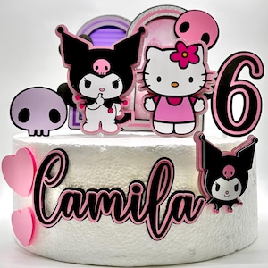 May include: A white cake decorated with pink and black Hello Kitty and Kuromi characters, a pink heart, a pink six, and the name "Camila" in pink and black lettering.