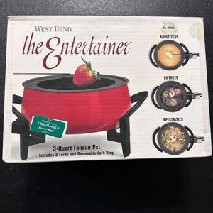 May include: A red West Bend "Entertainer" fondue pot with a strawberry on top. The box includes images of appetizers, entrees, and specialties. The box also states that the pot is 3-quart and includes 8 forks and a removable fork ring.